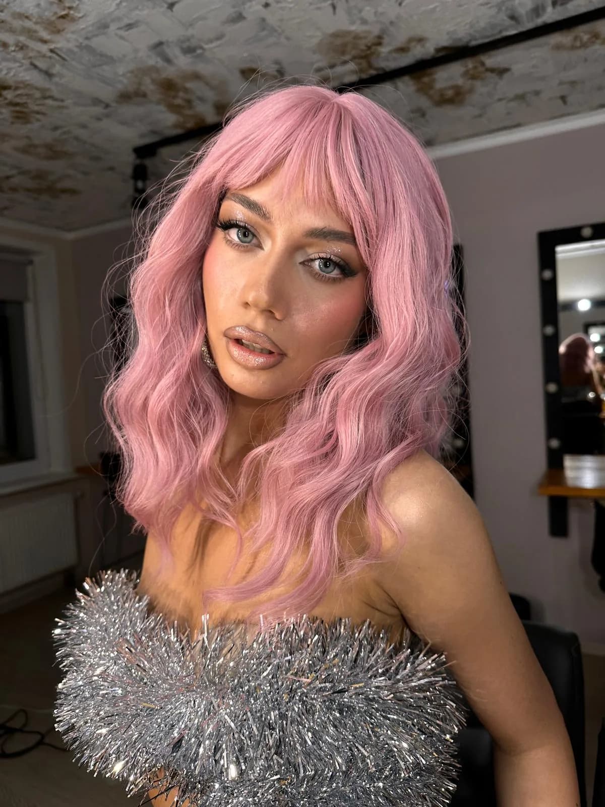 Ausdrucksstarkes Make-up mit rosa Haaren und silbernem Outfit